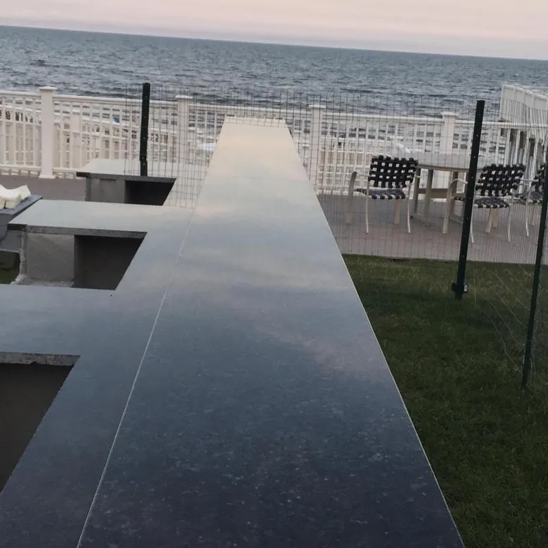 Polished black stone bar top running toward the ocean on a waterfront deck on Cape Cod